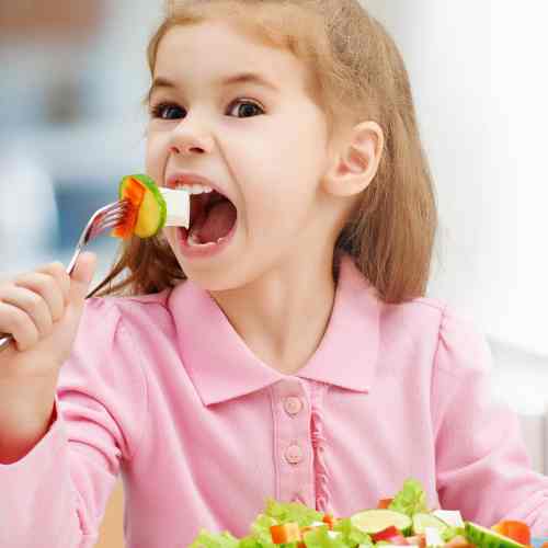 little girl eating bite of salad