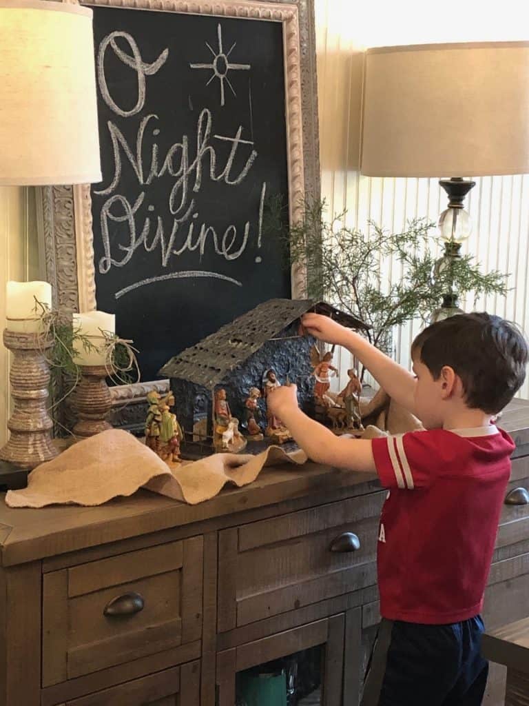 Little boy playing with nativity scene and sign that says O Night Divine