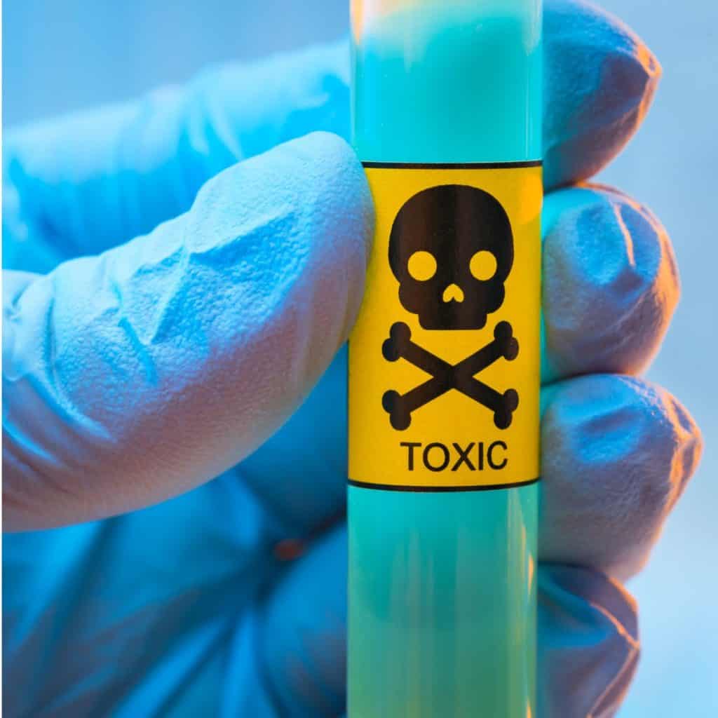 gloved hand holding test tube of toxic substance