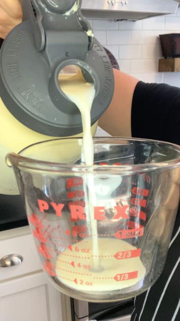 hand pouring raw milk into a measuring cup
