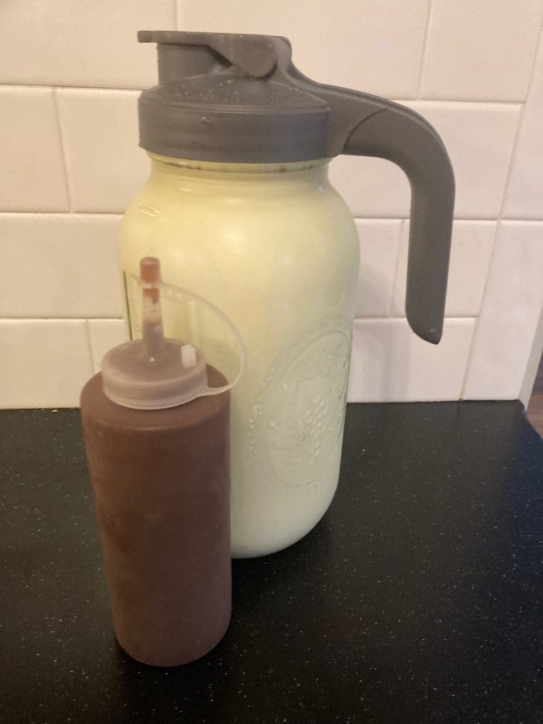 jug of raw milk with squeeze bottle of chocolate syrup