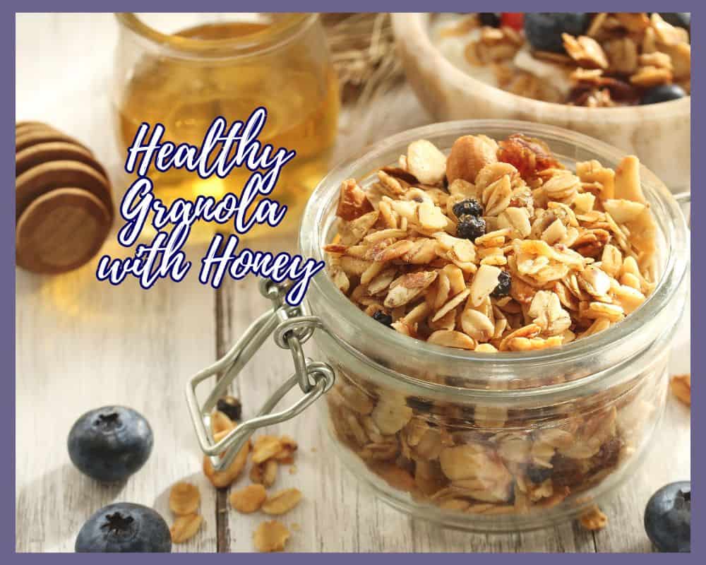 jar of granola and jar of honey with blueberries sprinkled around